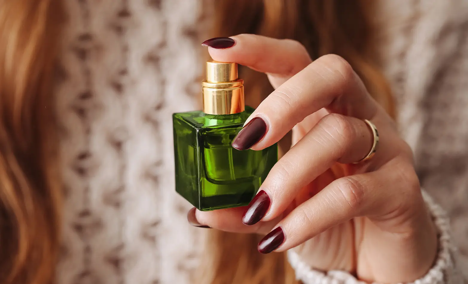 A photo of a perfume bottle in a manicured hand.