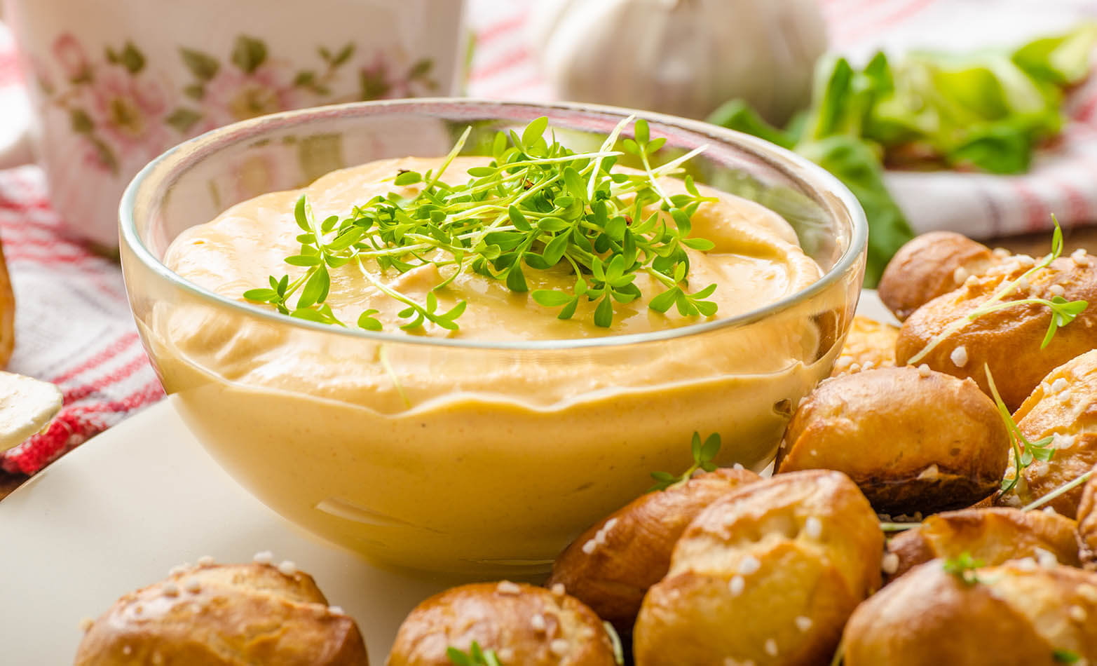a glass bowl of beer cheese dip served with pretzel bites