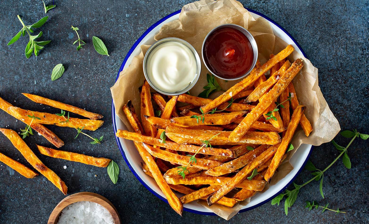 a bowl of sweet potato fries with two dipping sauces