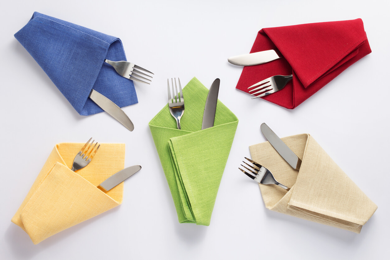 knife and fork in folded napkin at white background