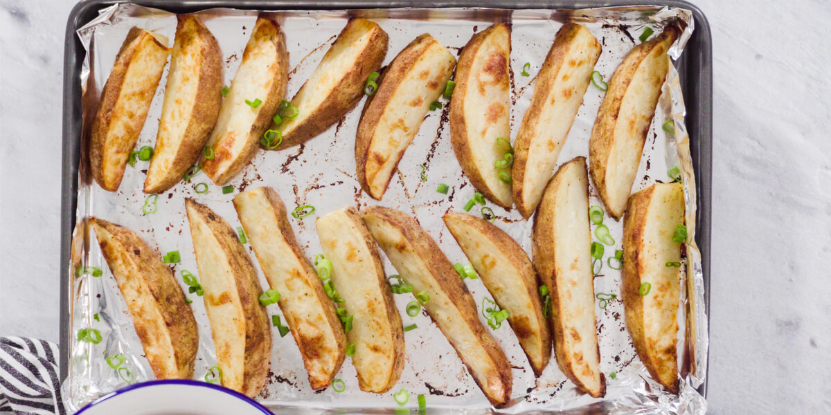 cut potato wedges on a baking sheet.