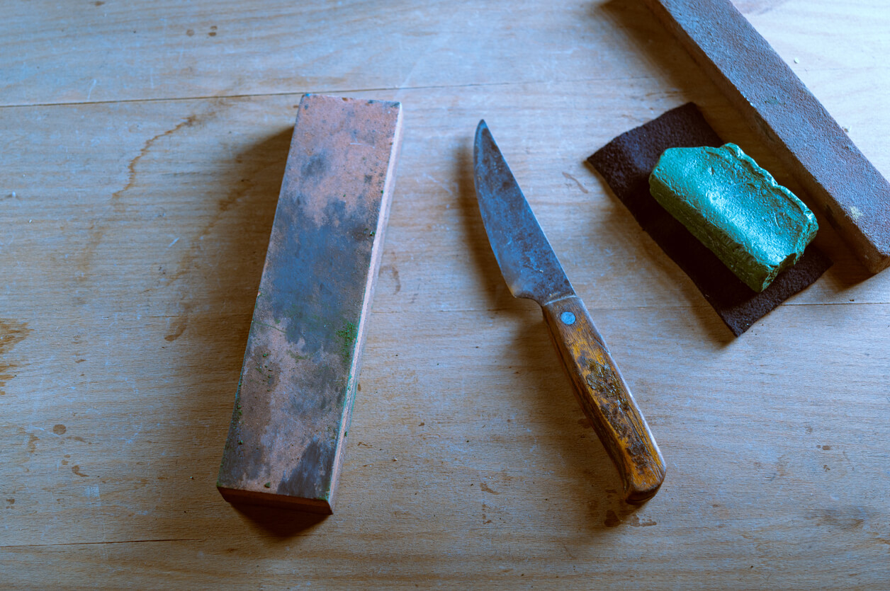 Old kitchen knives and whetstone. Sharpening stones and an old knife.