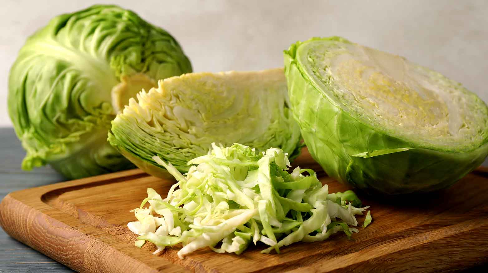 Several cabbages being chopped up on a wooden cutting board