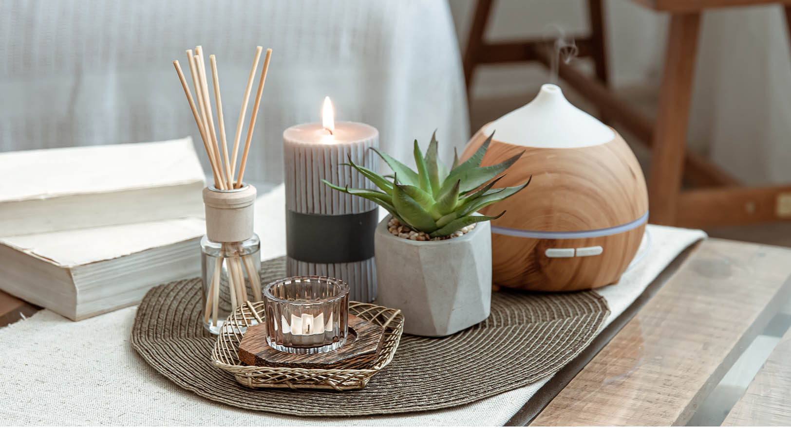 A photo of two small candles, incense sticks, a small succulent plant, and a diffuser on a side table.