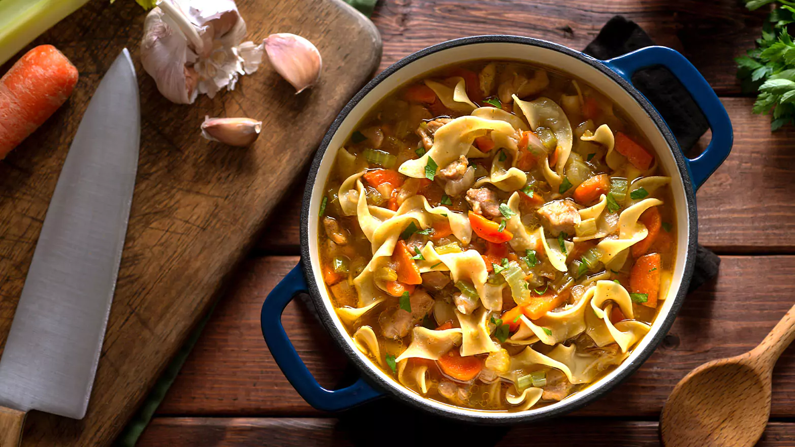 A top-down view of a big pot of chicken noodle soup.