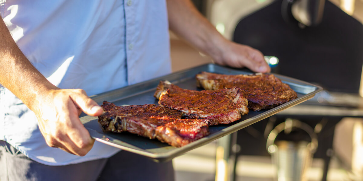 Carrying Grilled Steak on a Cooking Pan.