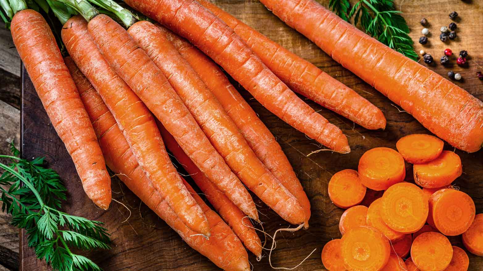 Carrots being chopped up on a wooden cutting board