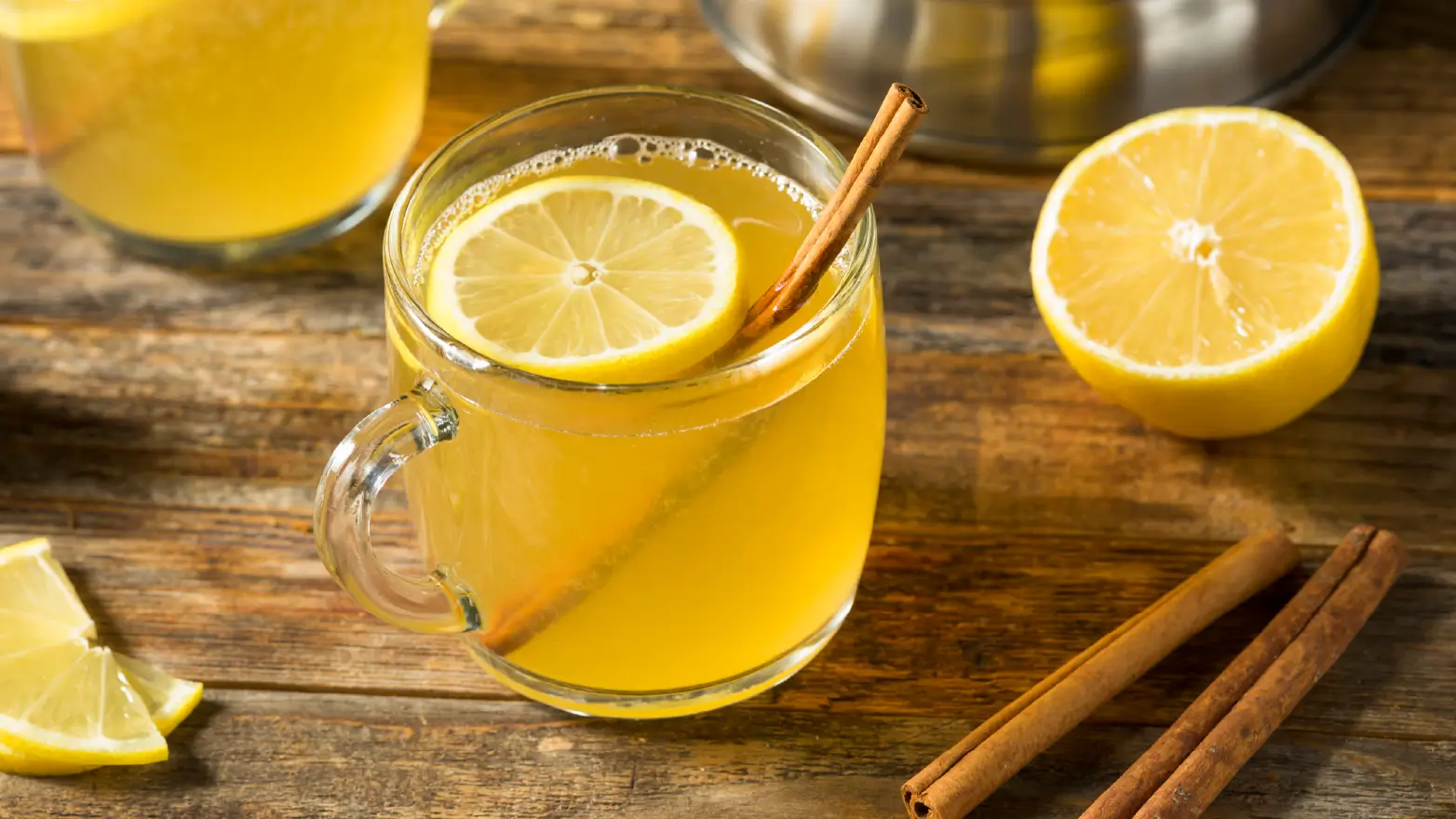 hot toddy drink in a clear glass with lemon and cinnamon garnishes