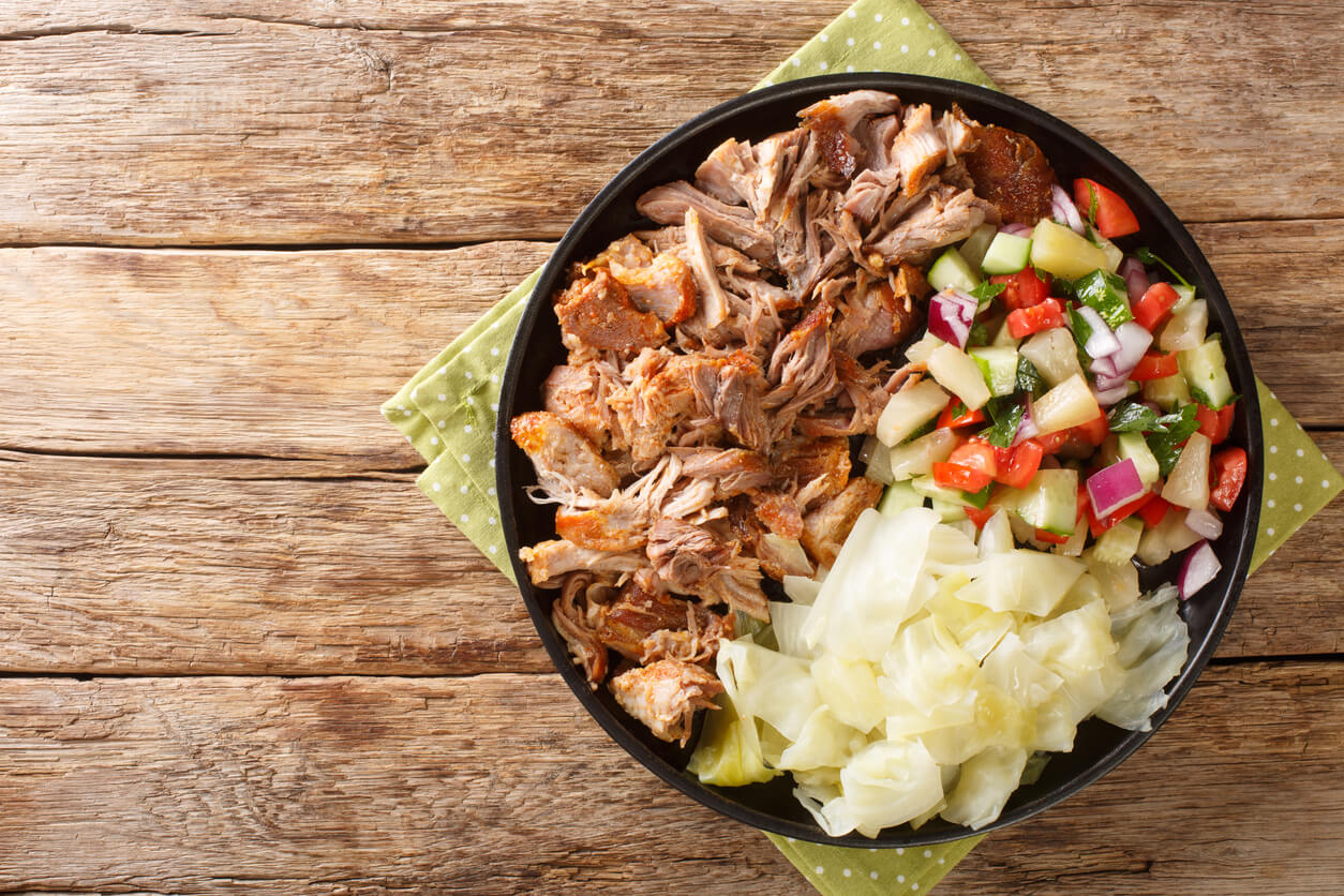 Kalua pork hawaiian food slowly cooked and served with stewed cabbage and fresh salad close-up in a plate on the table.