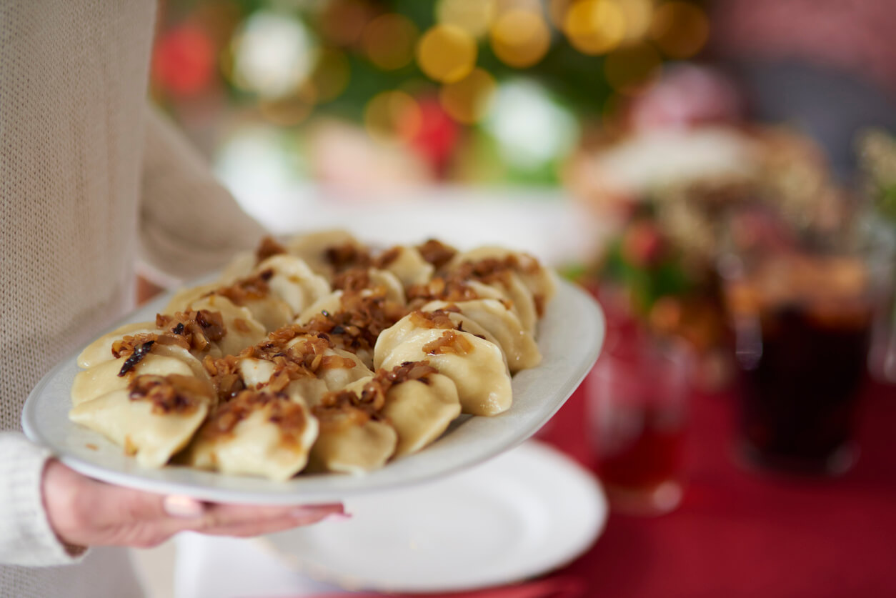 Woman serving plate full of dumplings.