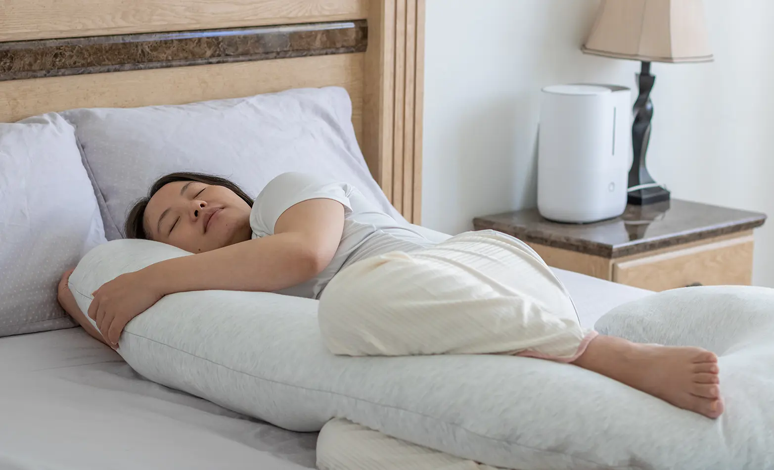 A photo of a woman snuggling a body pillow.