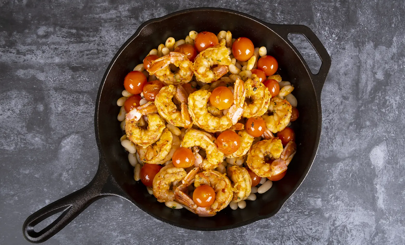 a cast iron filled with garlicky shrimp and white beans
