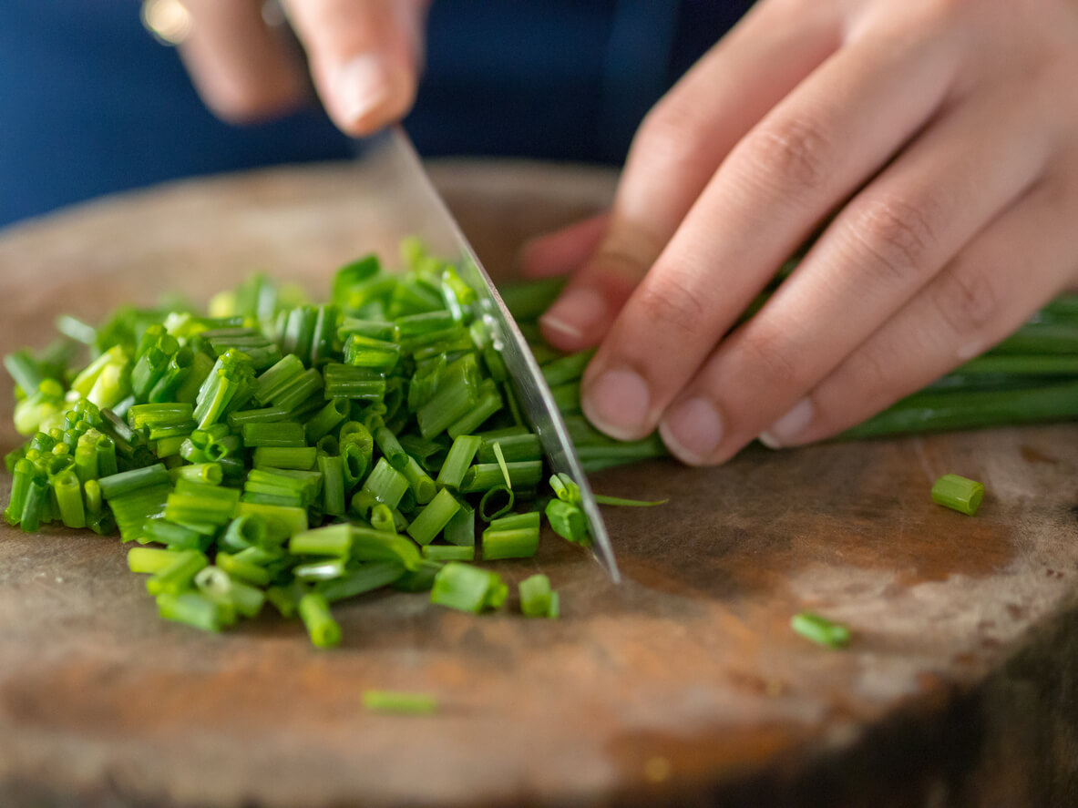 Hand cut Scallions on wooden cutting board.