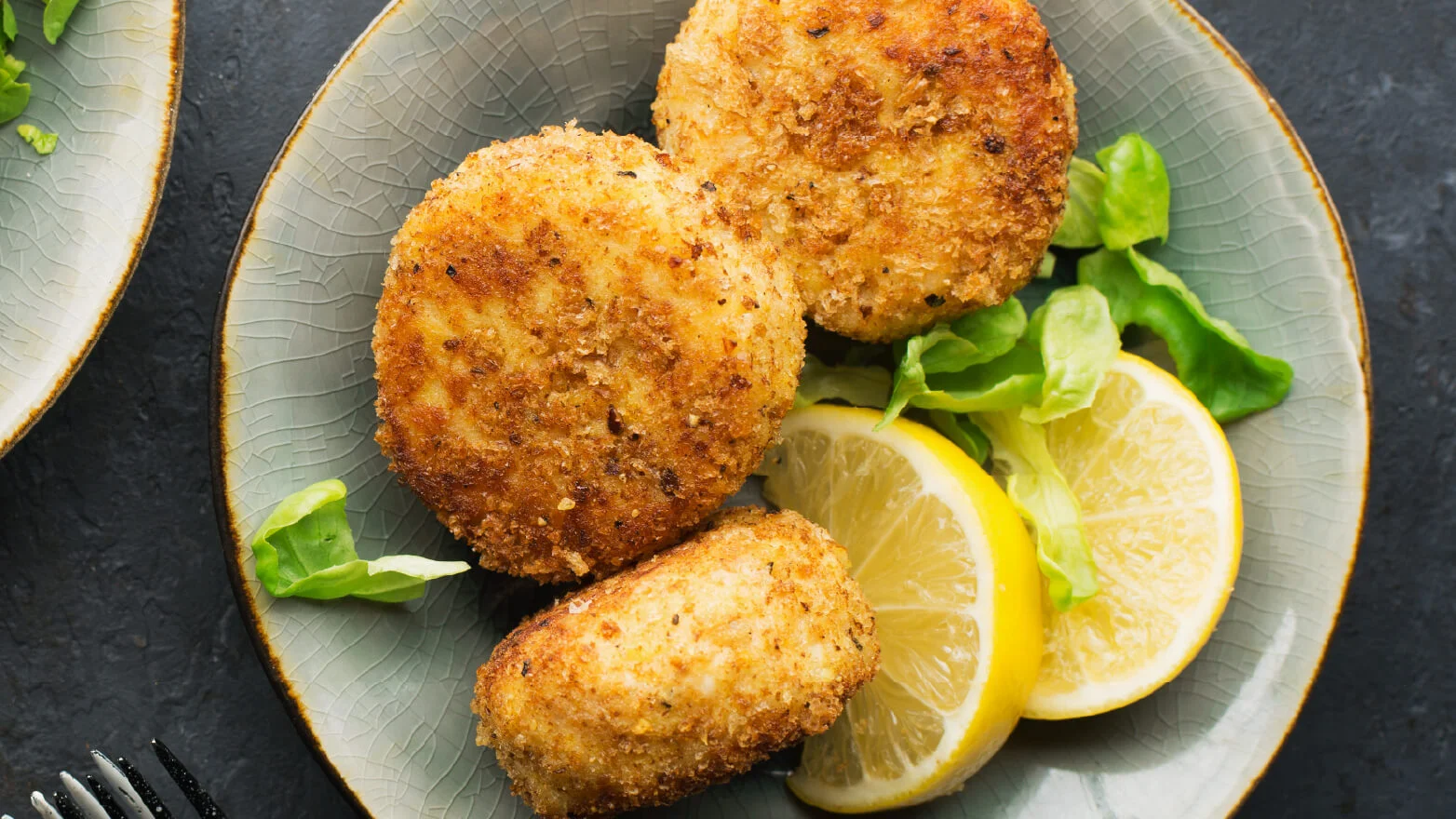 a photo of cracker crusted salmon patties on a plate with lemon