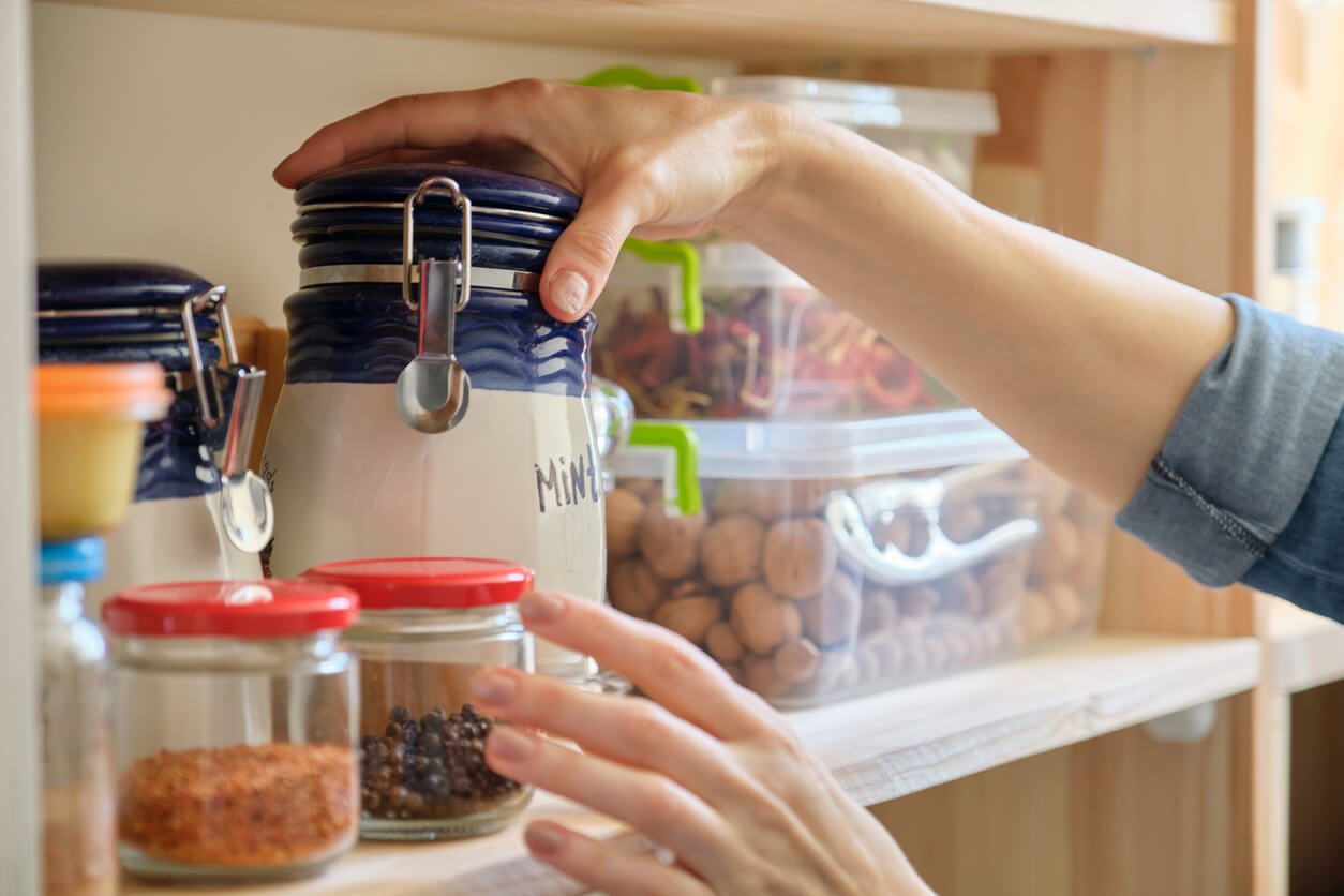 Woman in the kitchen with can of dry mint, food storage, pantry.