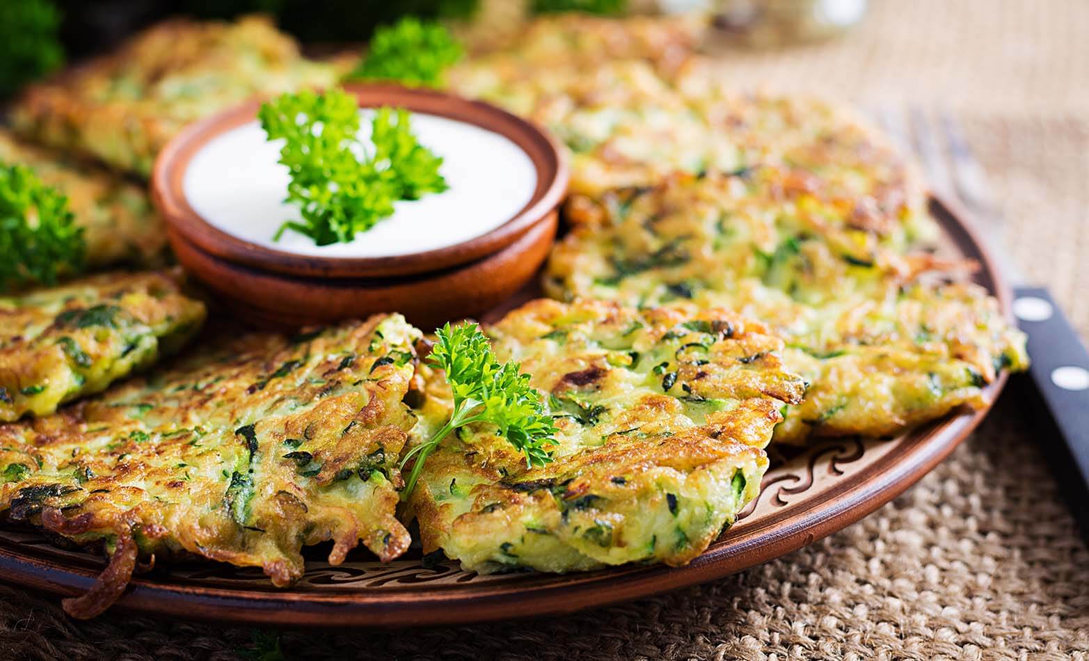 a platter of crispy zucchini fritters served with Greek yogurt dip