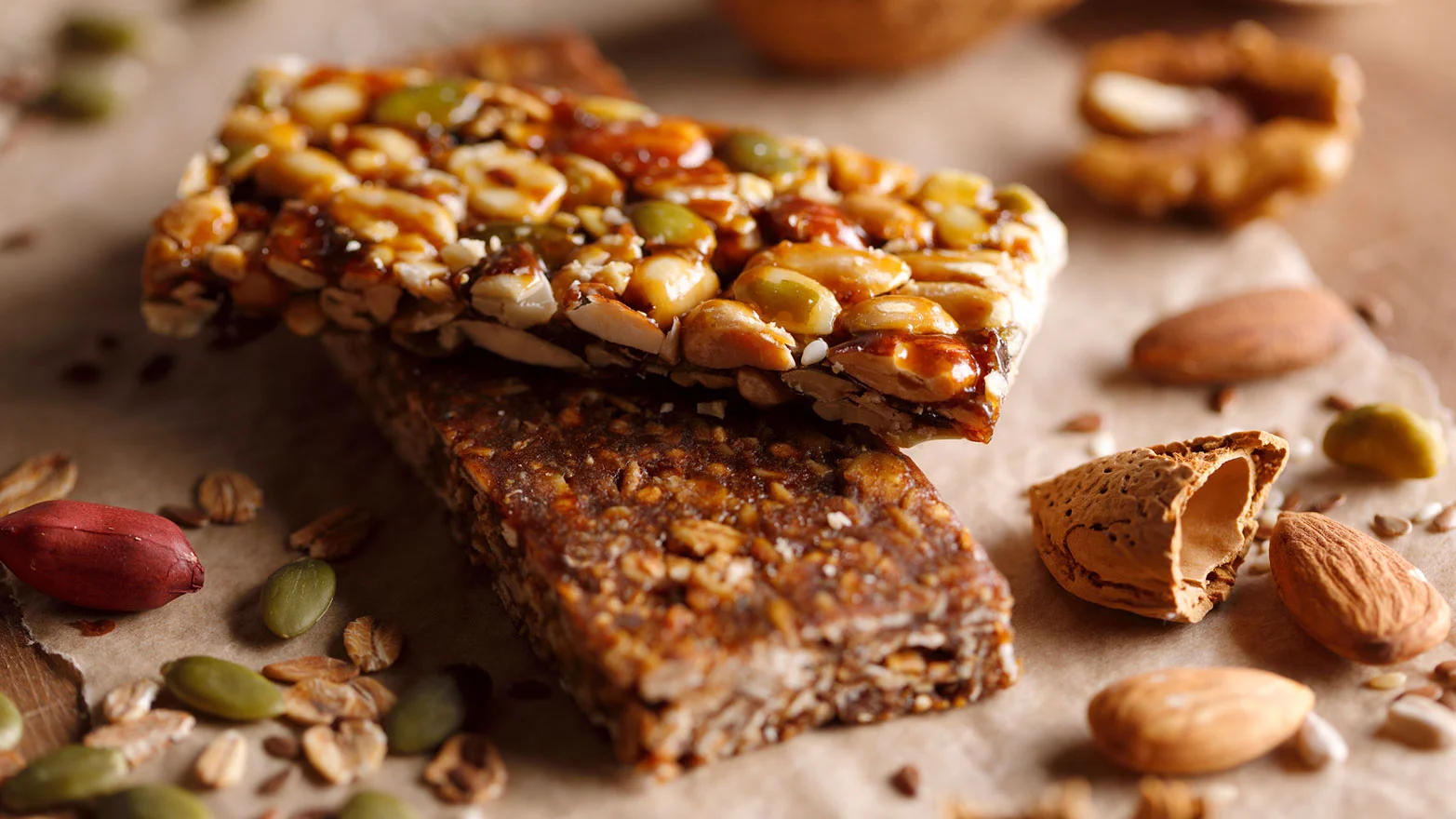 A close-up stock photo of a stack of protein bars and granola bars surrounded by nuts.