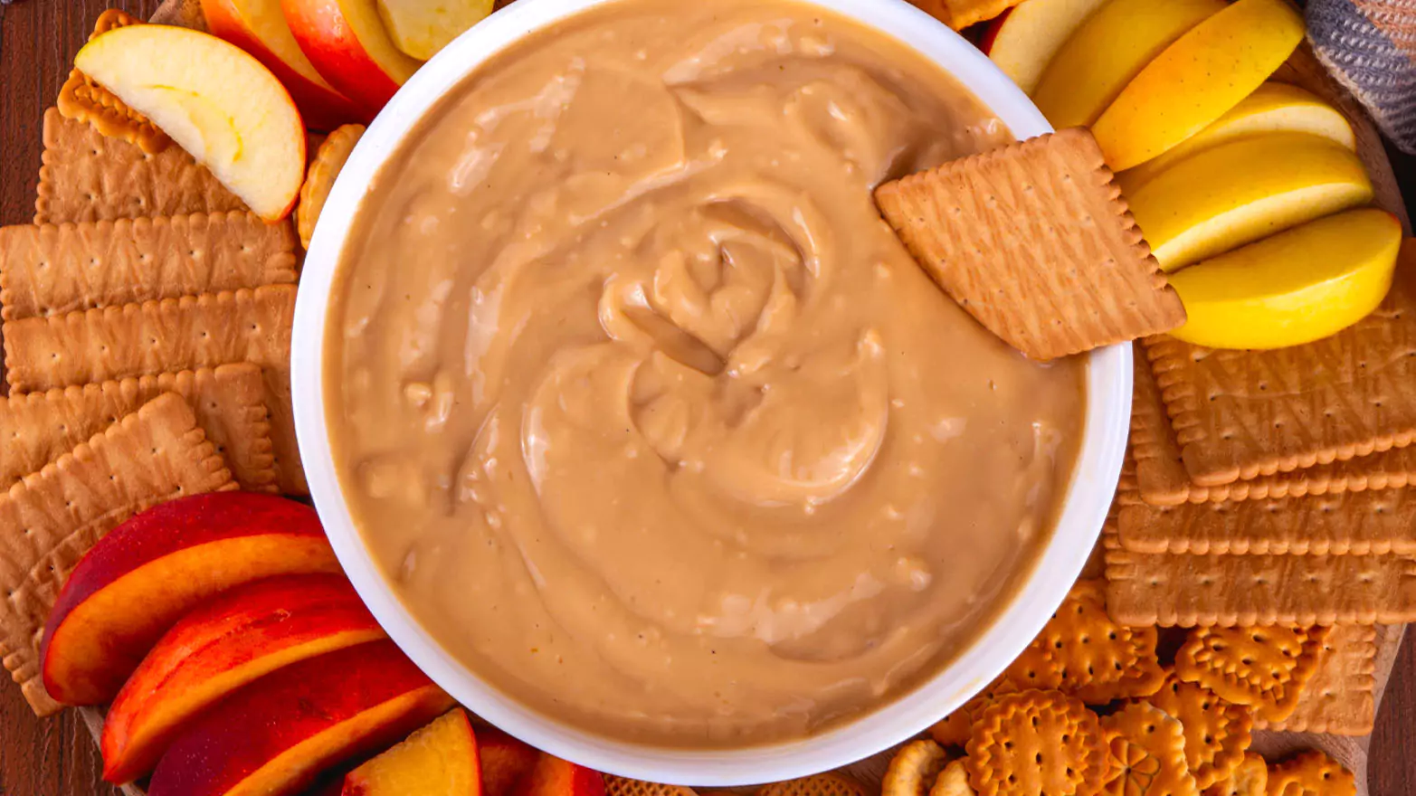 A bowl of pumpkin pie dip served with fruit and crackers