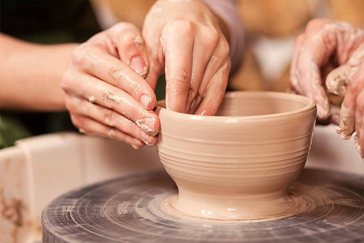 a close-up of a couple’s hands at a pottery class