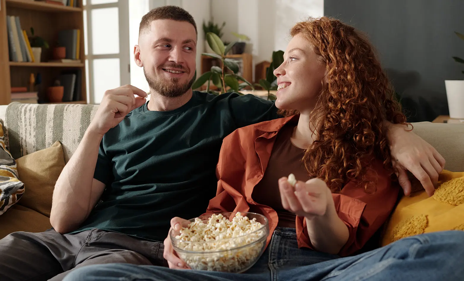 A photo of a couple enjoying a bowl of popcorn.