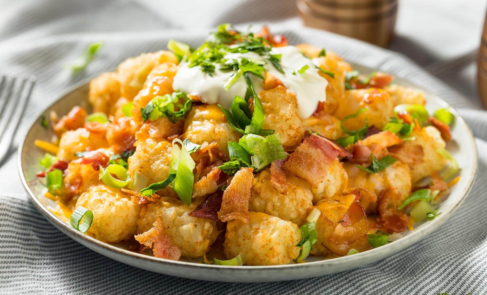 a plate of loaded tater tots topped with sour cream
