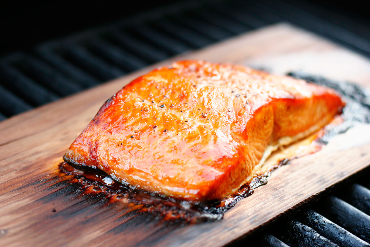 Salmon fillet with coarse ground pepper, grilled over a cedar plank.