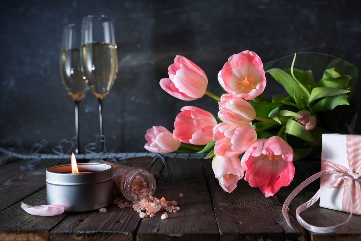 Atmospheric mothers day decoration with bouquet of pink tulips and gift on dark vintage wood.
