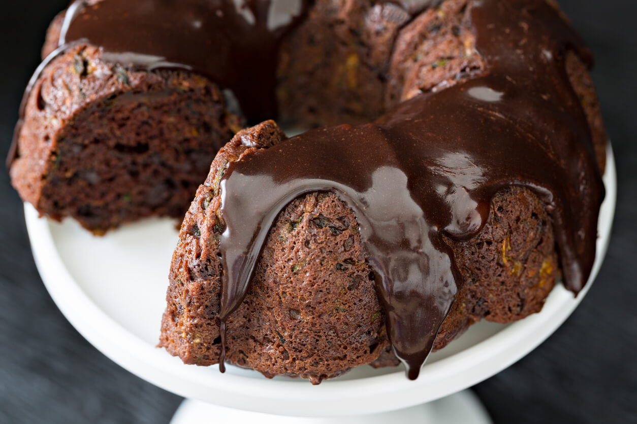 An extreme close up shot of a zucchini chocolate bundt cake glazed with ganache.
