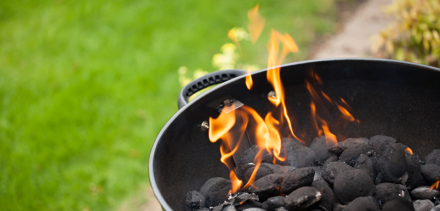 Barbecue with flames just being lit with lawn in background