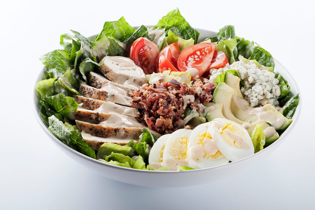 Fresh salad of romaine greens, sliced chicken breast, tomatoes, bacon, avocado, boiled egg, and blue cheese.