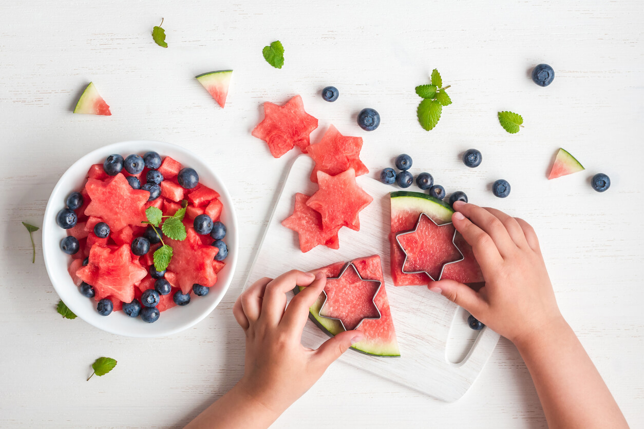 children's hands cutting stars out of watermelon
