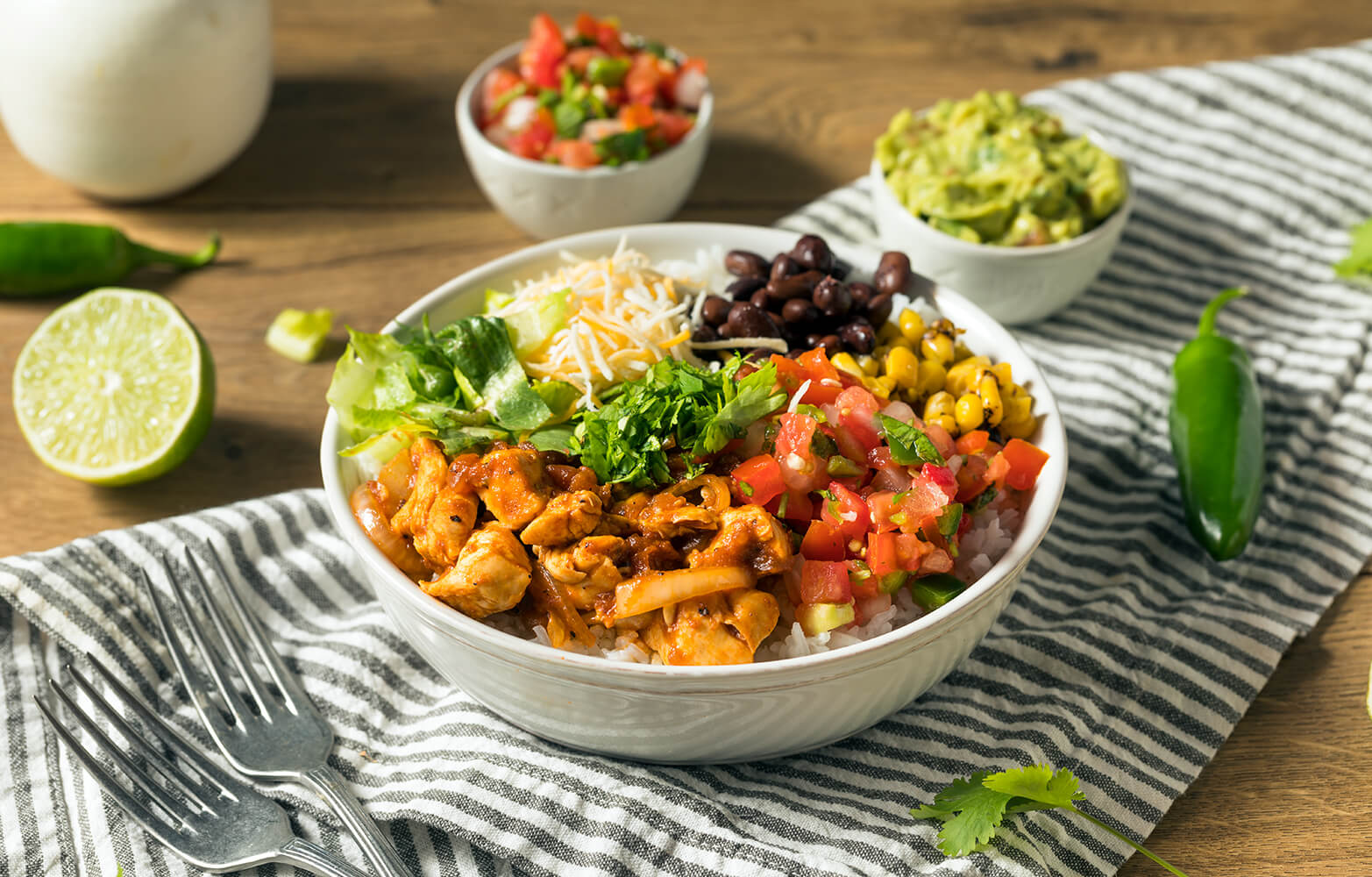 a stock photo of a chipotle burrito bowl with guacamole and pico de gallo sides