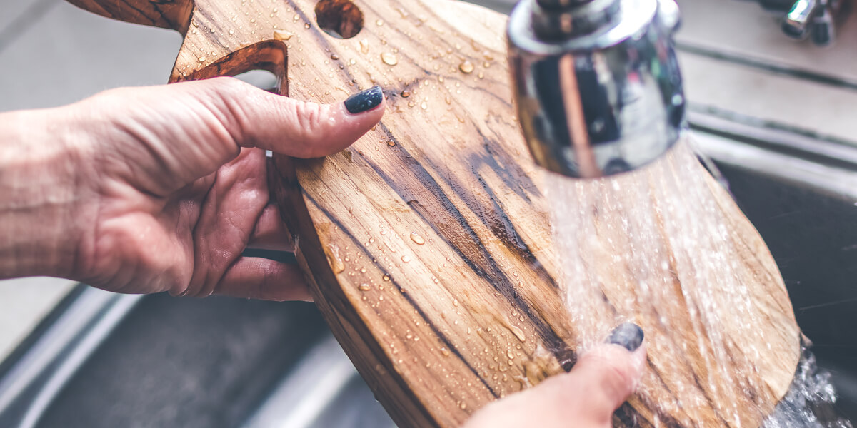 Cleaning a wooden cutting board in the sink.