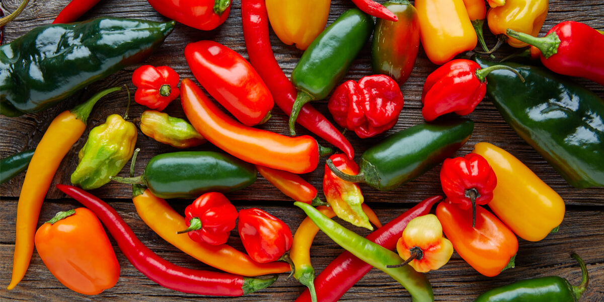 a colorful mix of many peppers on a dark wood background
