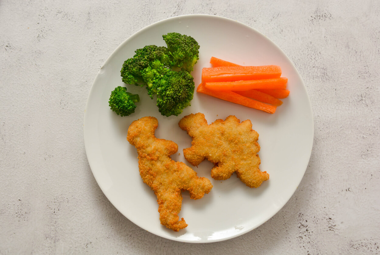 Kids food. nuggets with vegetables. Dinosaur shaped chicken, fish or turkey nuggets, ready to eat.