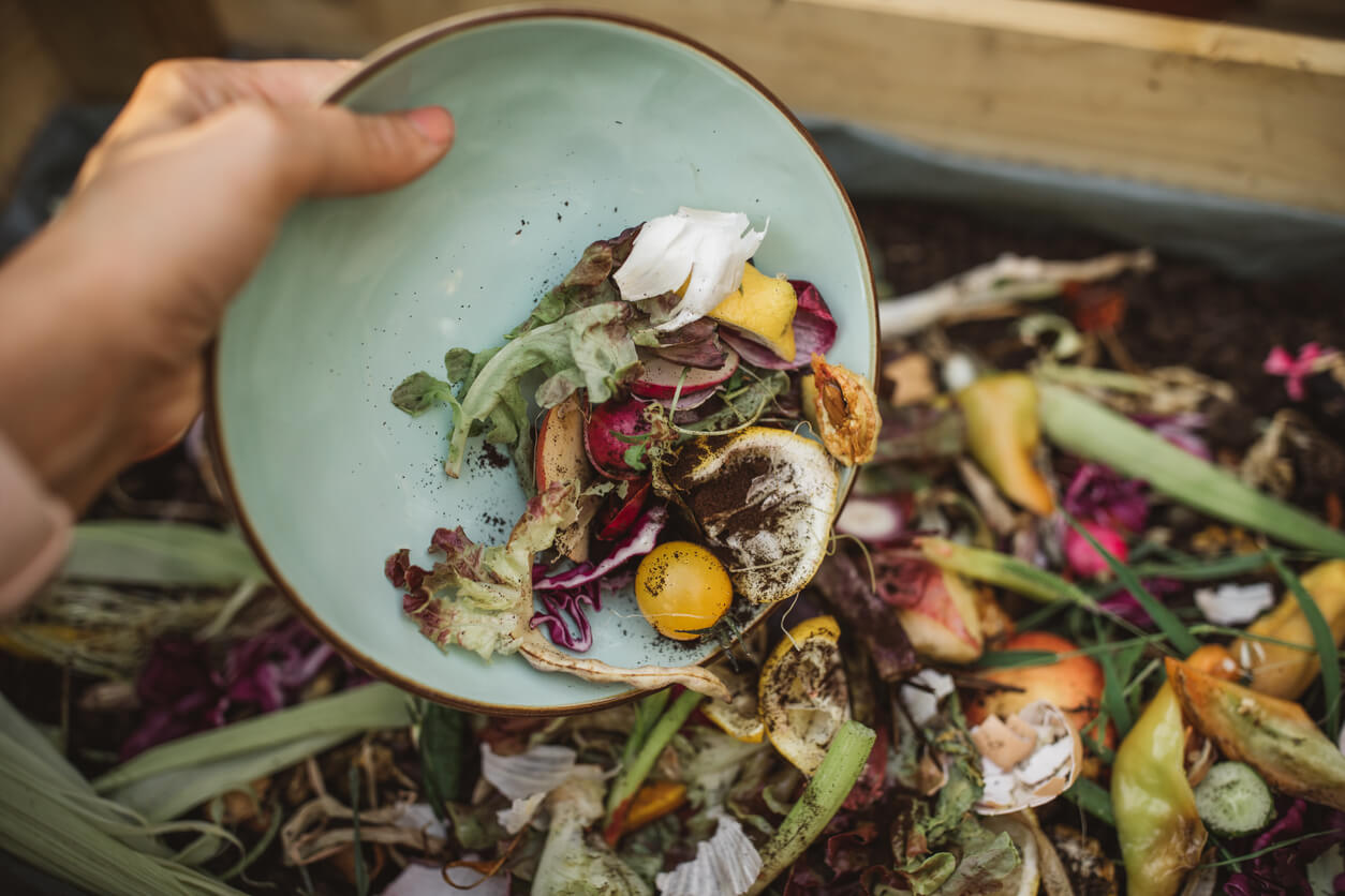 After preparing vegetable meal for cooking, women making compost from leftovers.