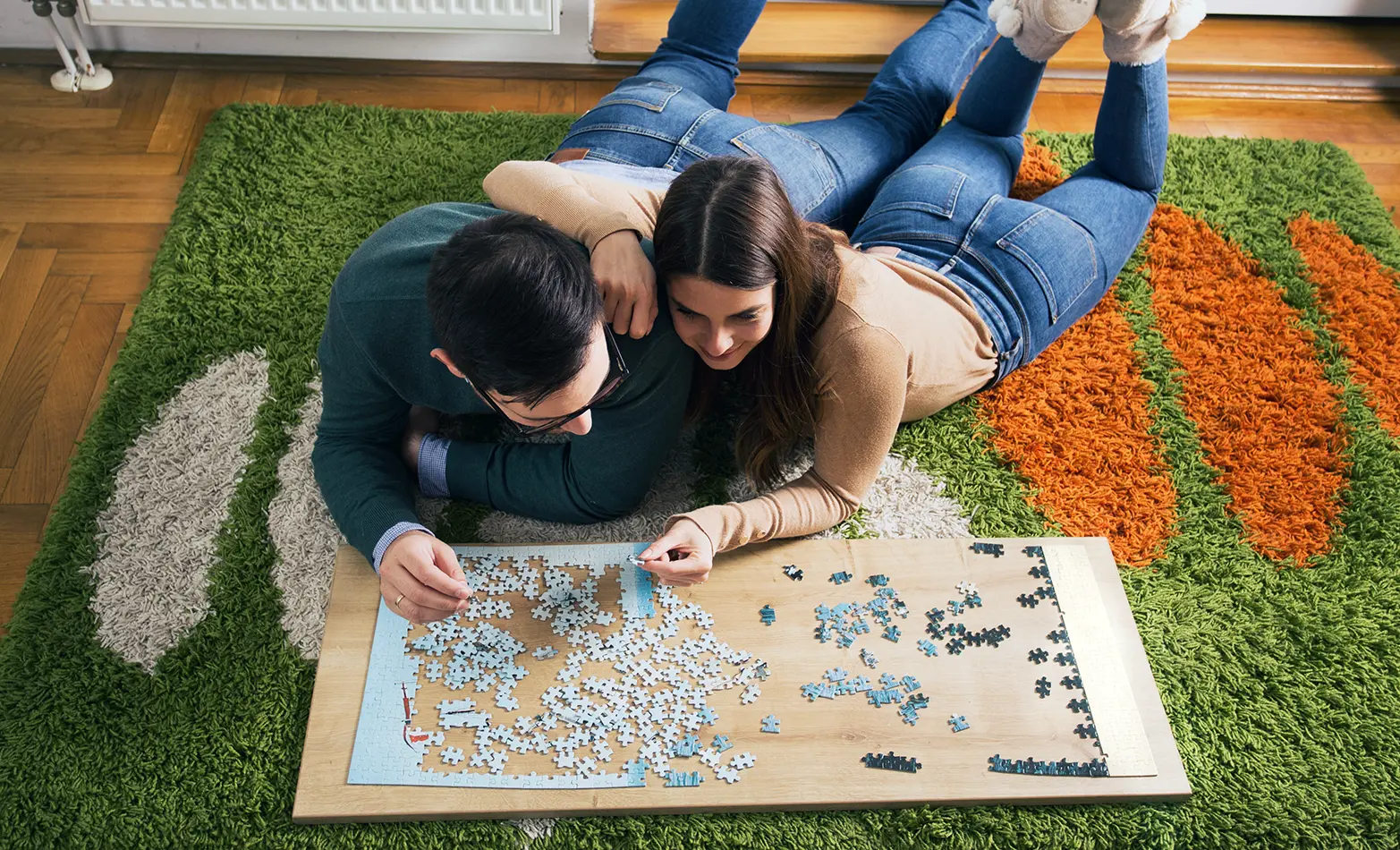 A photo of a couple completing a jigsaw puzzle.