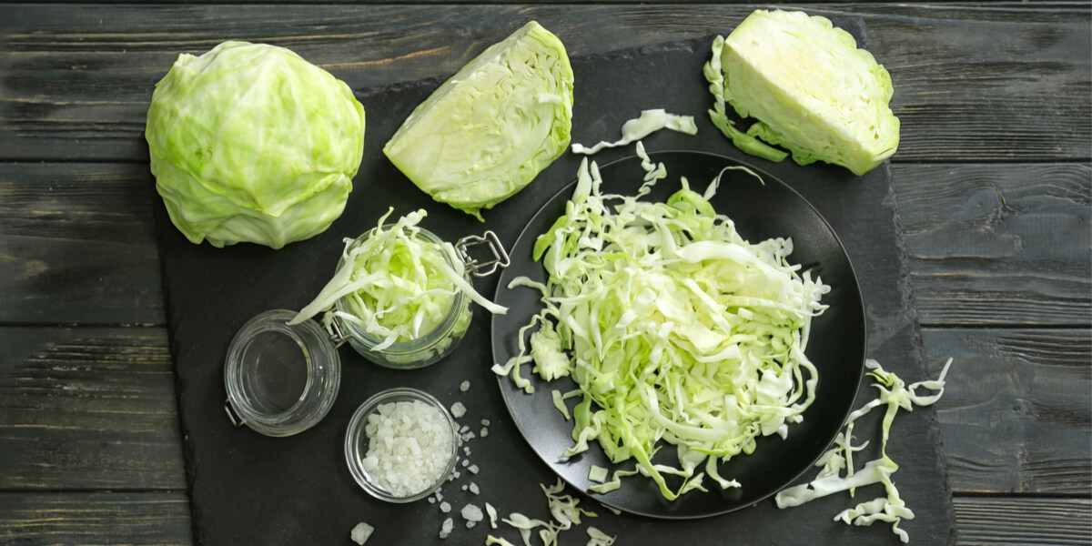 cabbage in various degrees of chopped on a cutting board