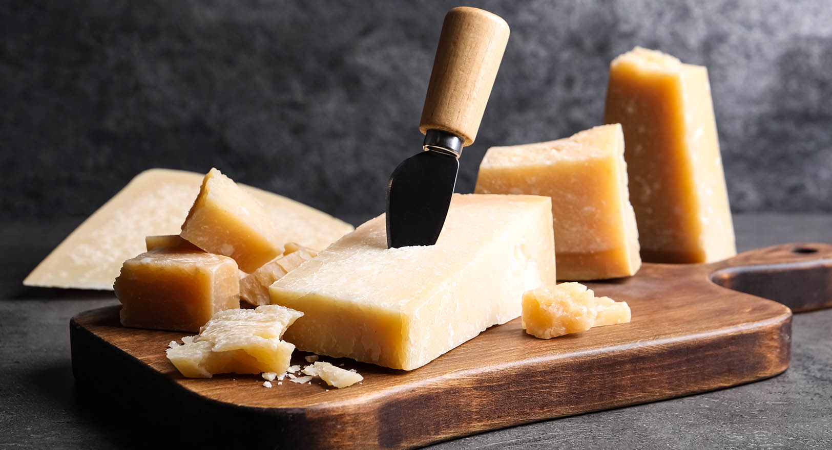 A large block of cheese on a wooden serving board.