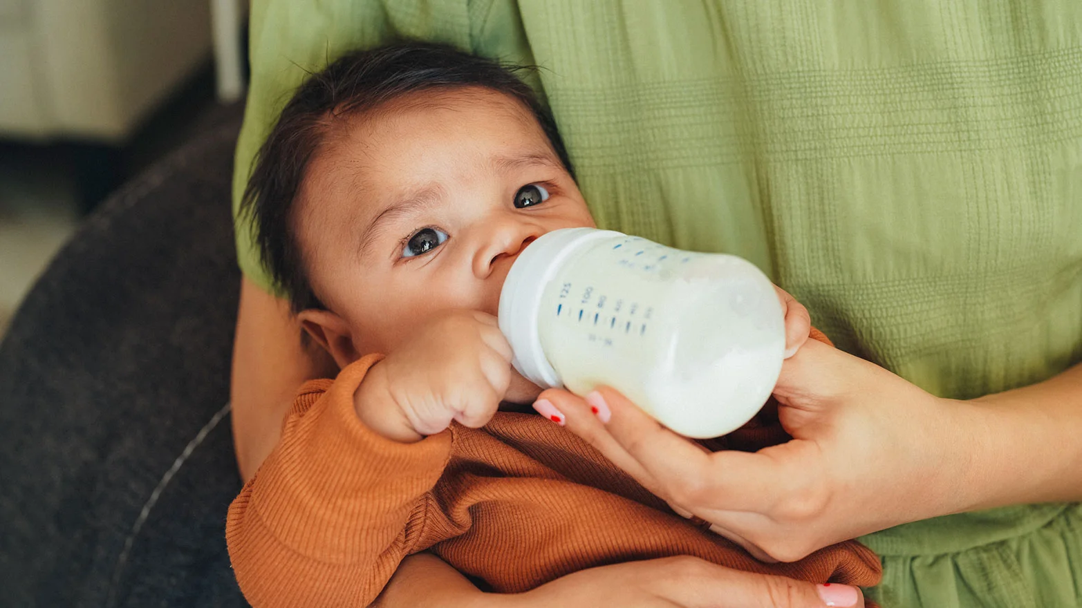 A stock photo of a baby drinking from a baby bottle.