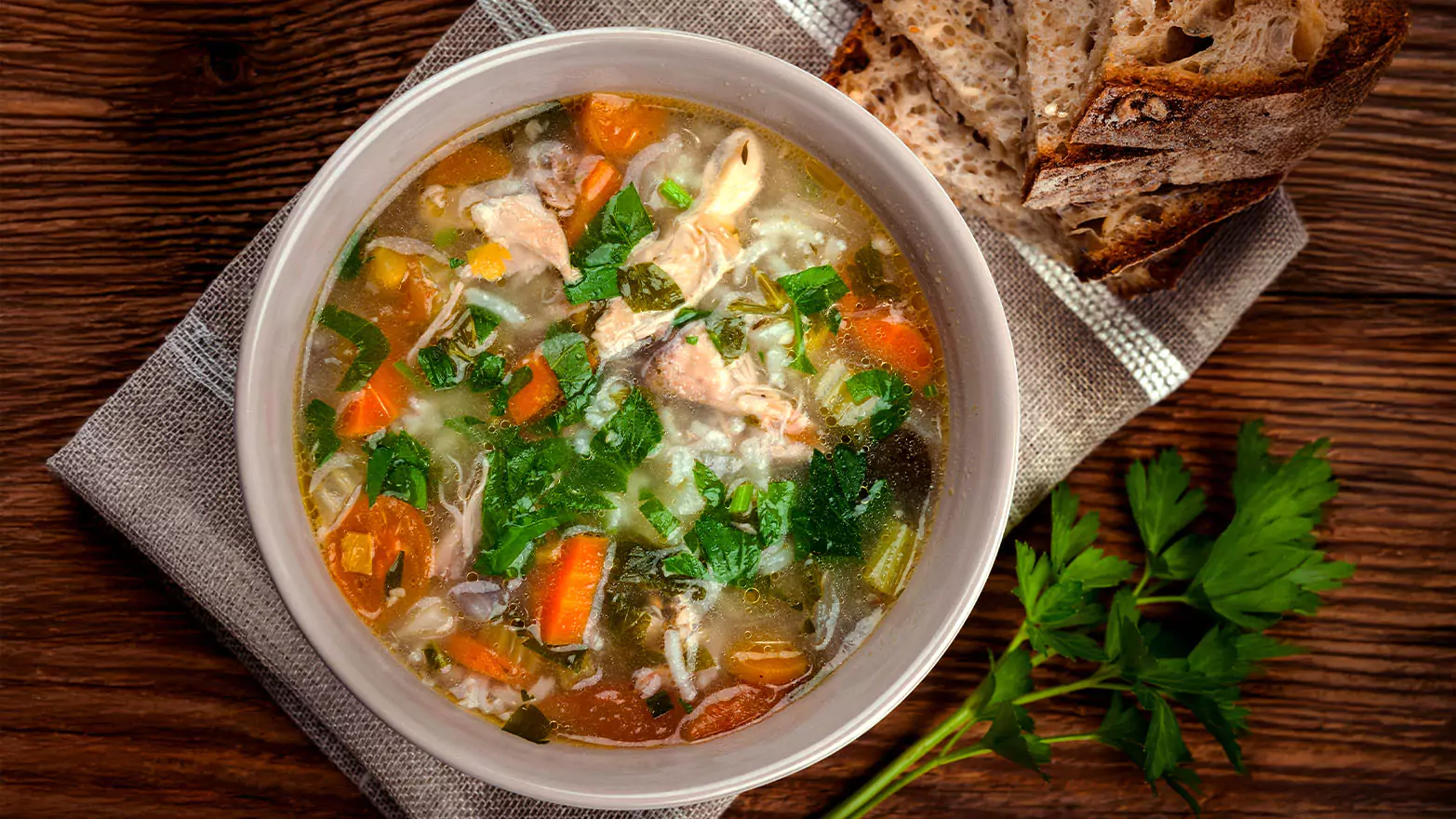 A bowl of leftover turkey soup served with bread.