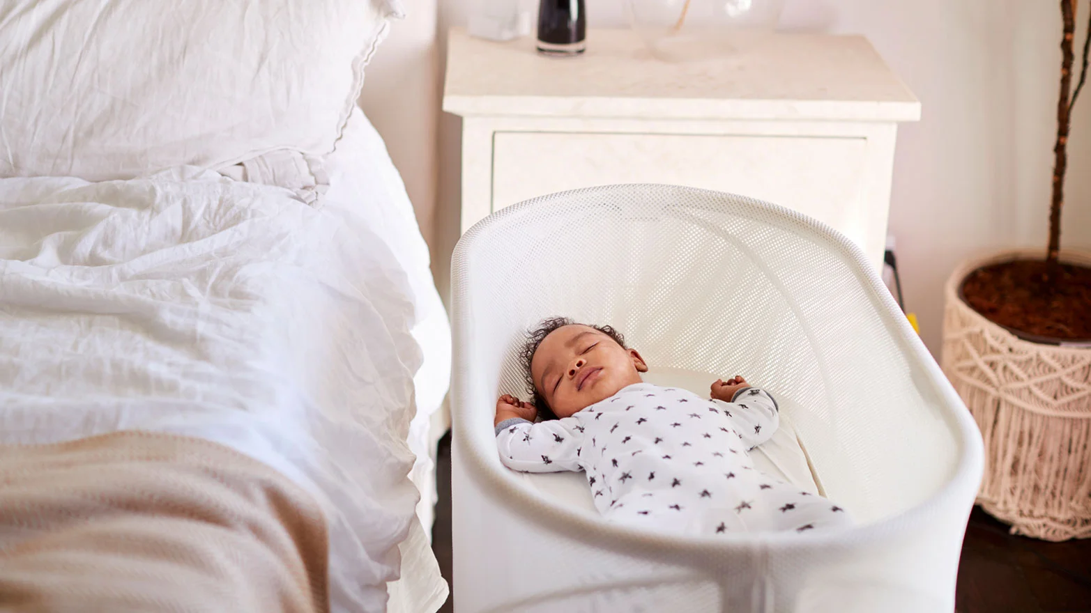 A stock photo of a baby in a bassinet next to the parents’ bed.
