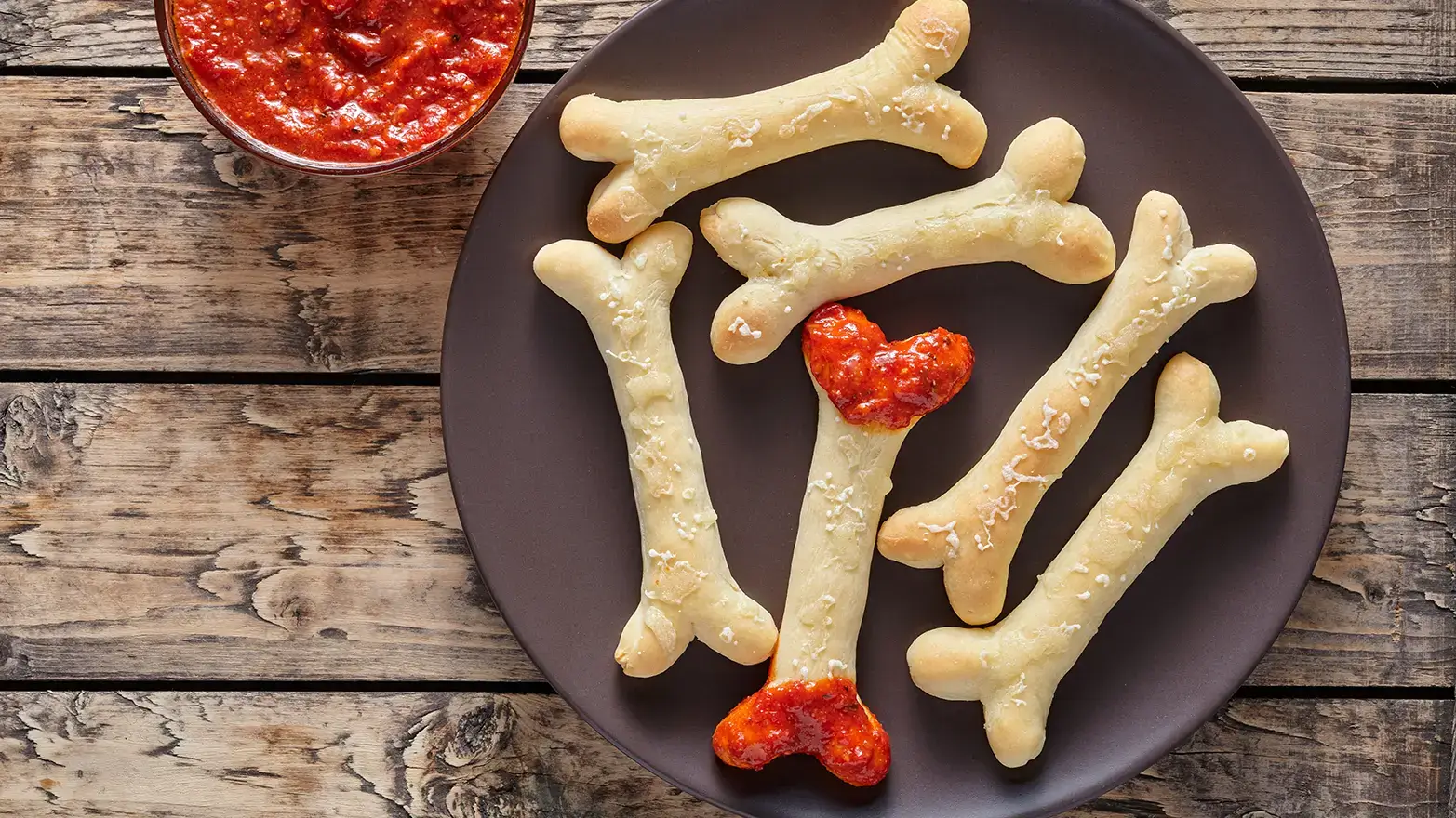 Breadsticks shaped like bones dipped in marinara