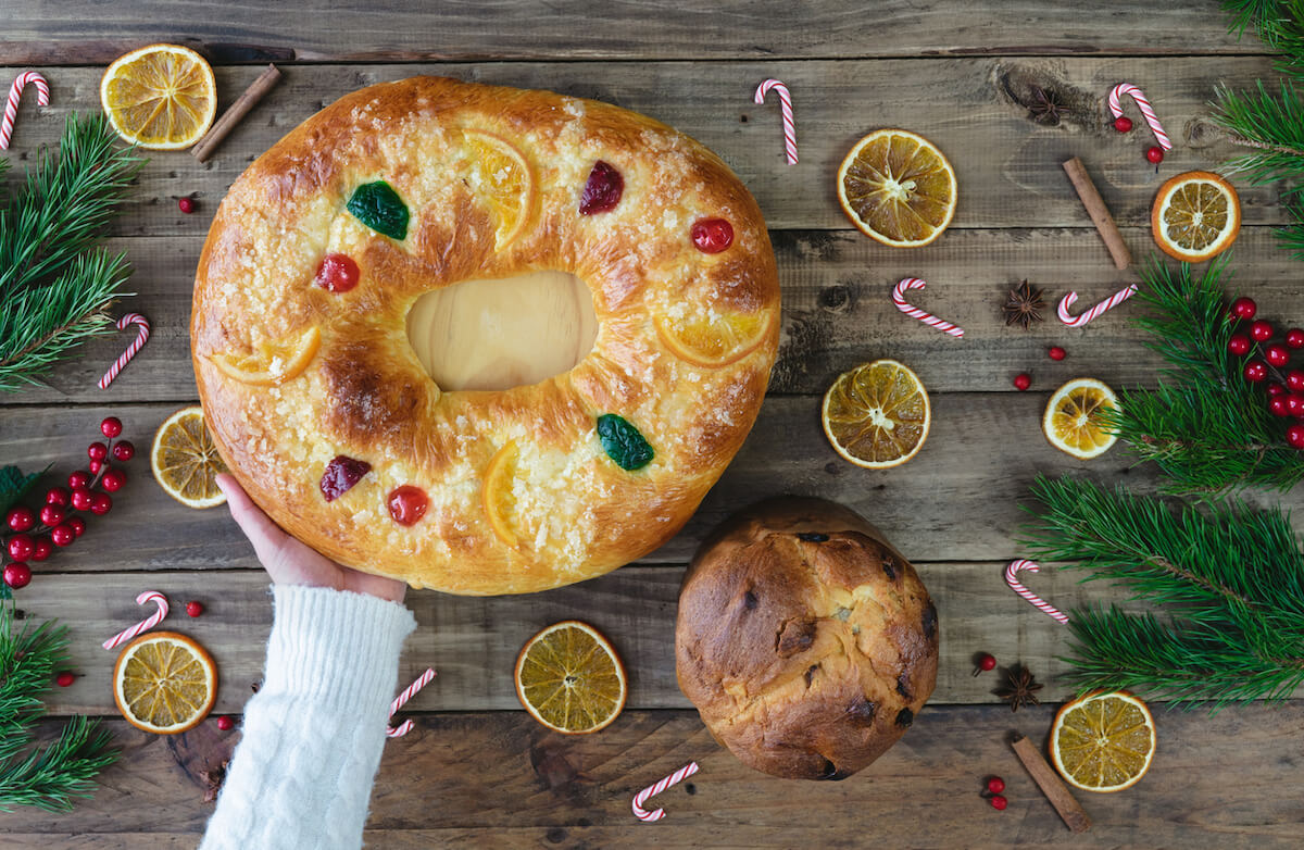 Roscon de Reyes and panettone on a wooden base with Christmas decorations.