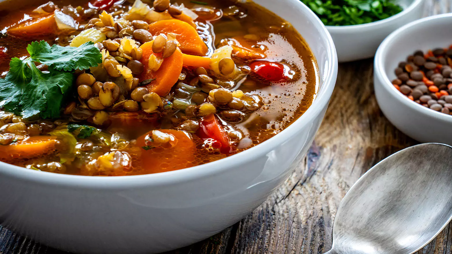 A colorful bowl of Mediterranean lentil soup with a spoon.
