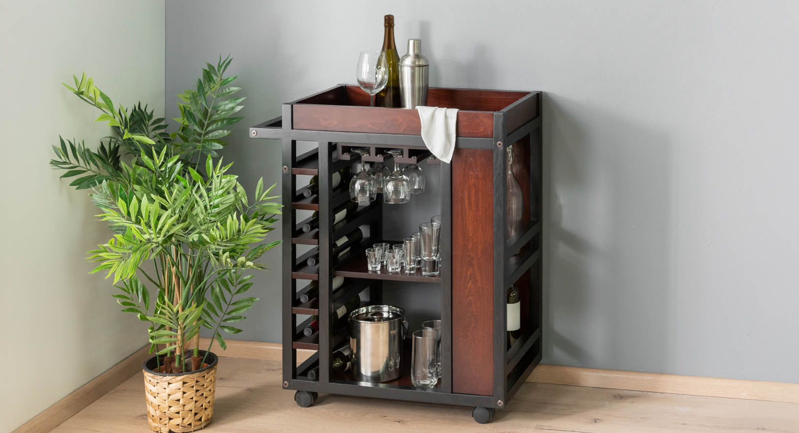 A photo of a small bar cart next to an indoor plant.