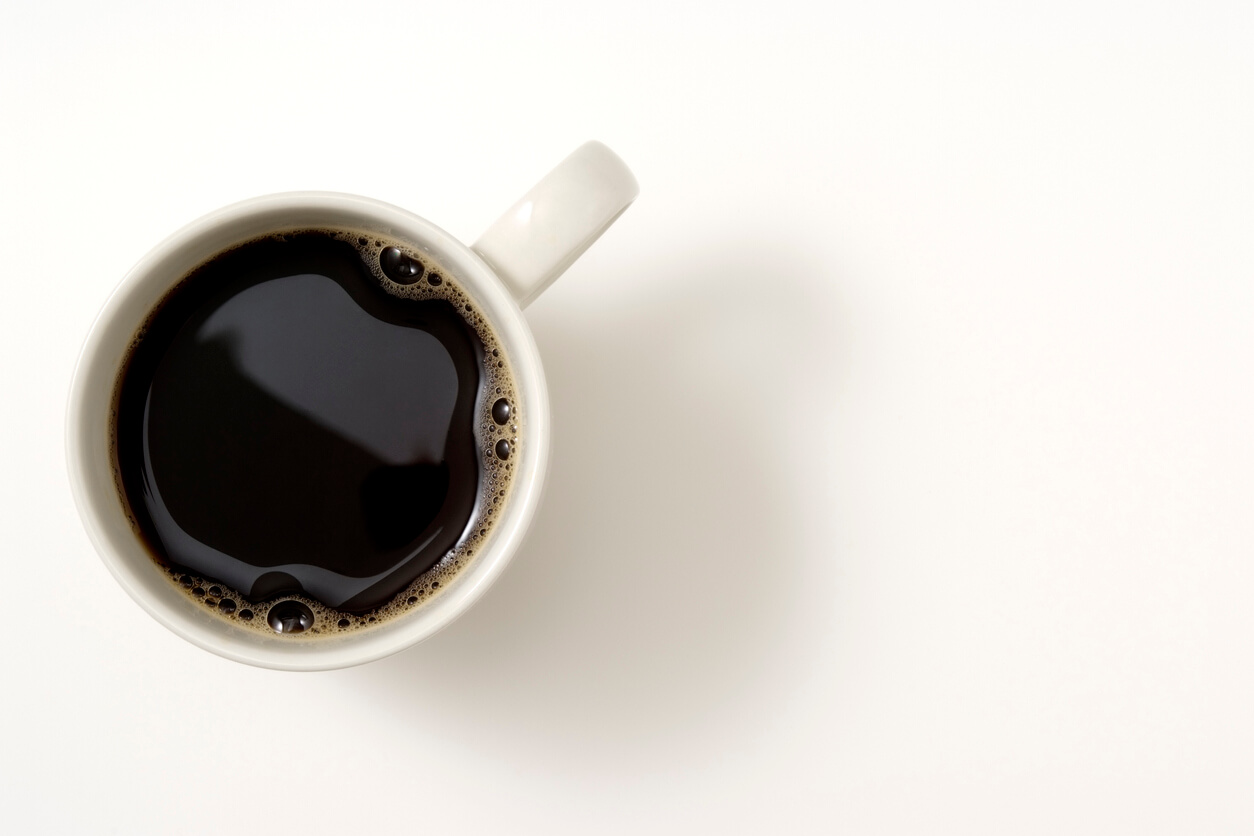 Overhead shot of a cup of coffee isolated on white background with soft shadow.
