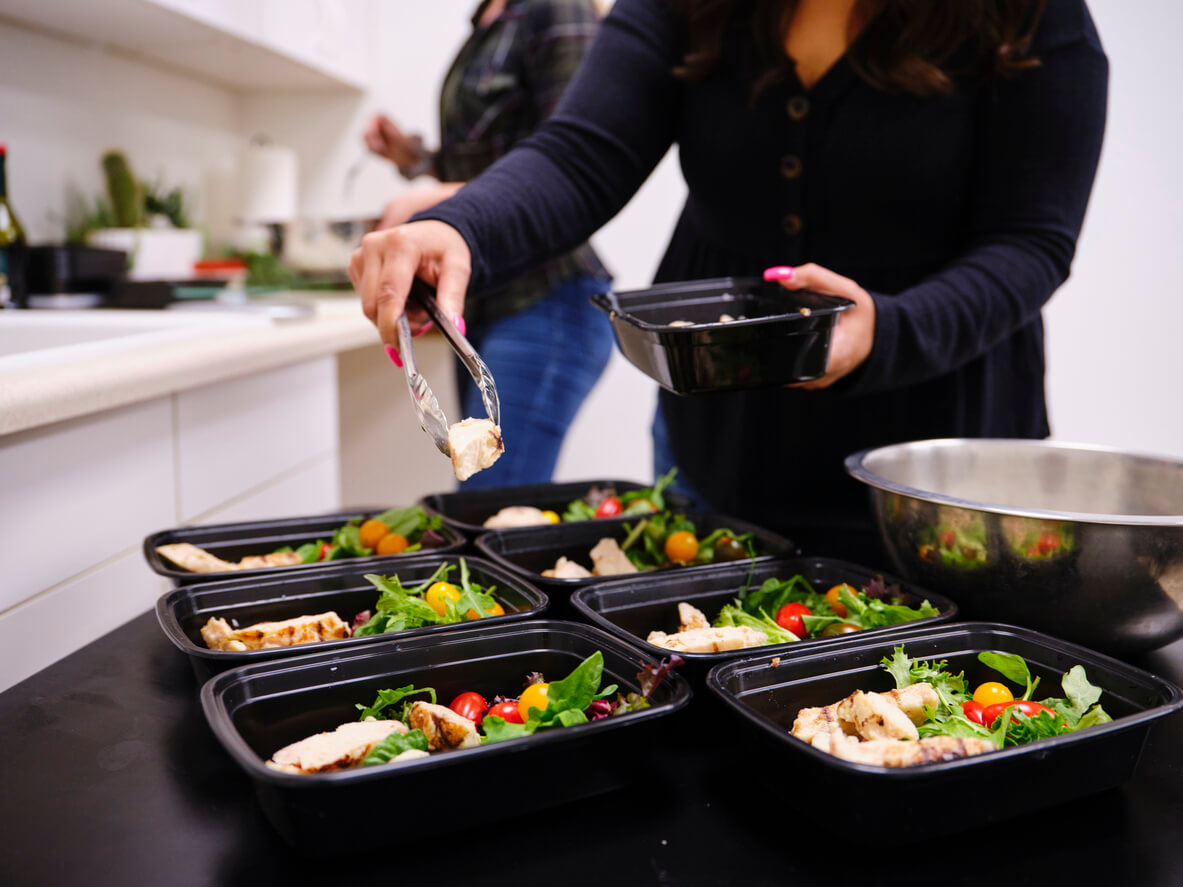 A woman prepares a healthy meal in her kitchen, using a scale to portion the ingredients.