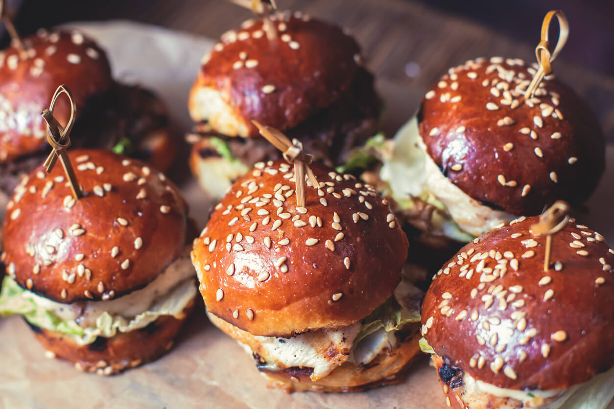 Burger mini burgers snacks on a wooden table with craft paper, beautifully decorated catering banquet table.