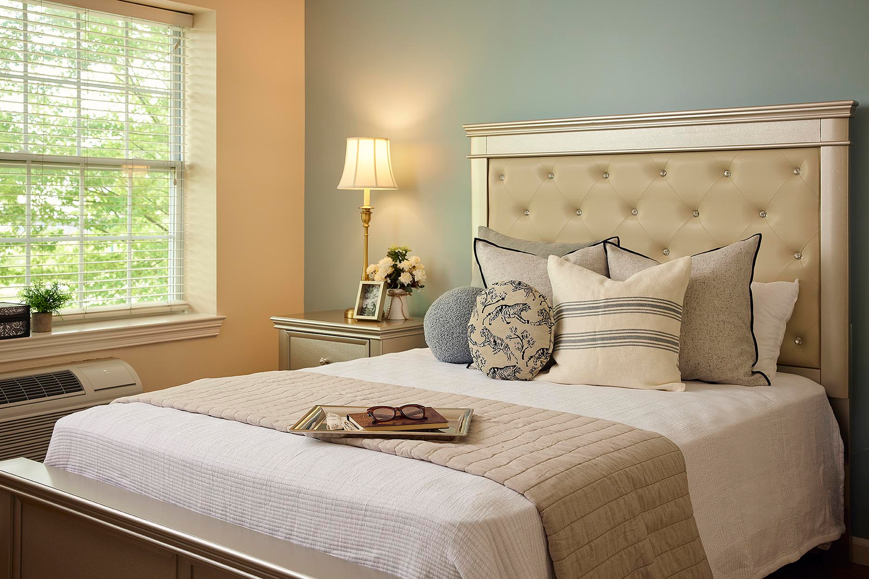 A double bed with a tufted headboard and fresh blue and white linens